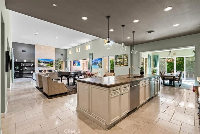 kitchen featuring recessed lighting, a sink, stone tile floors, dark countertops, and dishwasher