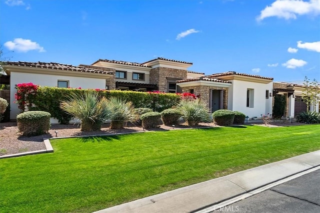 mediterranean / spanish-style home featuring stone siding, a front lawn, a tile roof, and stucco siding