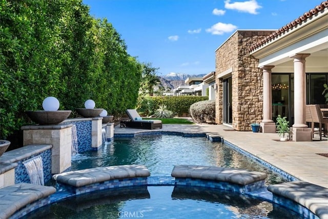 view of swimming pool with a pool with connected hot tub, a mountain view, and a patio