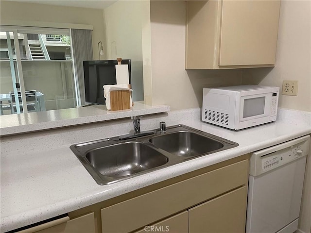 kitchen featuring white appliances, light countertops, and a sink