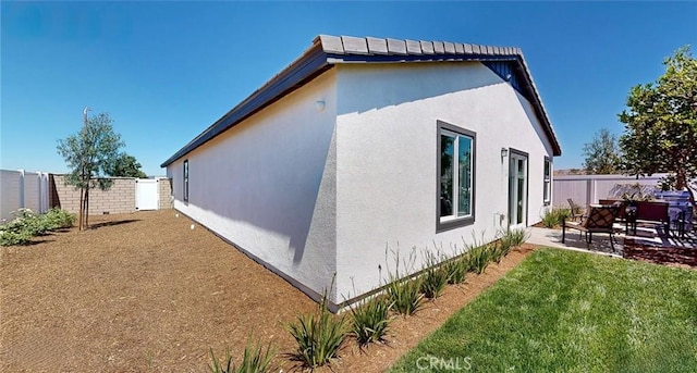 view of side of home featuring a fenced backyard, a patio, and stucco siding