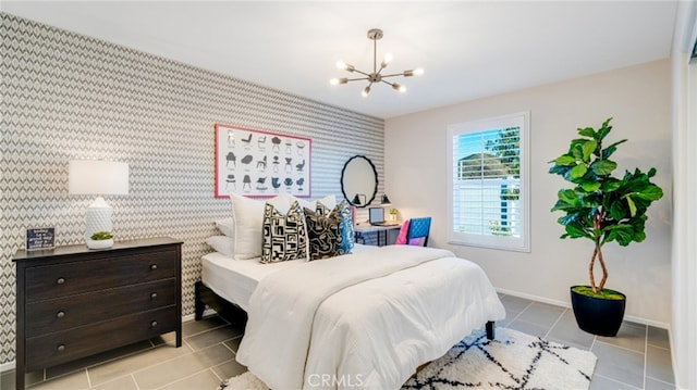 bedroom with light tile patterned floors, a notable chandelier, an accent wall, baseboards, and wallpapered walls