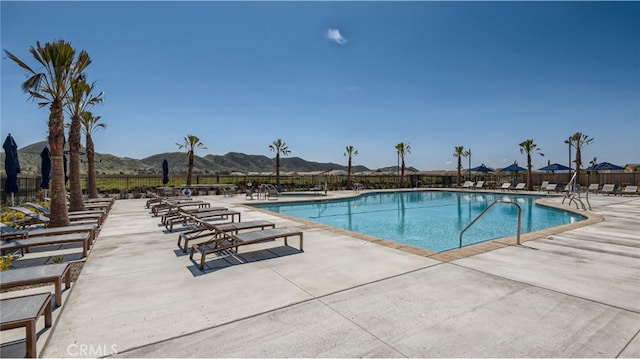 community pool featuring a patio area, fence, and a mountain view