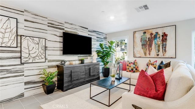 living room featuring light tile patterned floors, an accent wall, visible vents, and recessed lighting