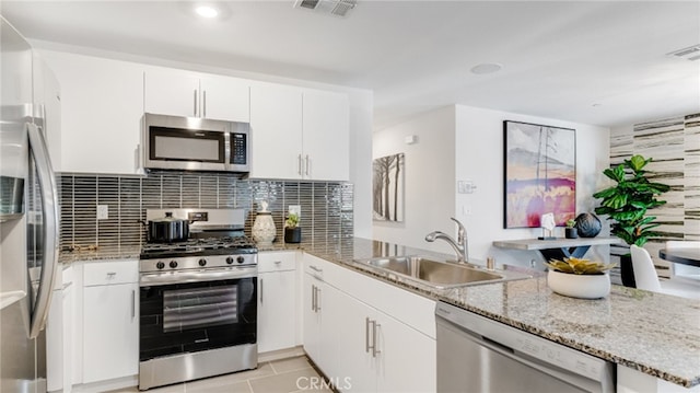 kitchen with visible vents, appliances with stainless steel finishes, white cabinetry, a sink, and light stone countertops