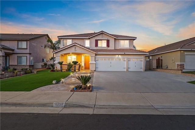 traditional home with a tile roof, stucco siding, an attached garage, driveway, and a front lawn