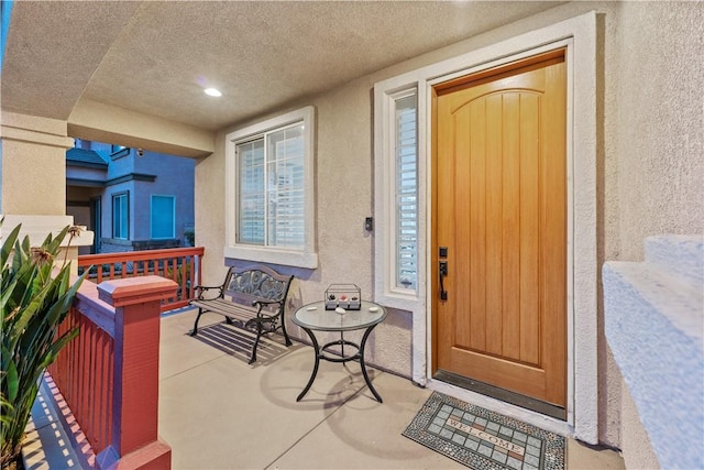 entrance to property with a porch and stucco siding