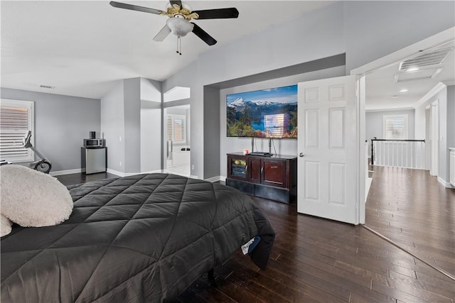 bedroom with a ceiling fan, ensuite bath, baseboards, and dark wood-type flooring