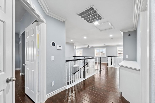 hallway featuring attic access, visible vents, dark wood-style floors, ornamental molding, and an upstairs landing