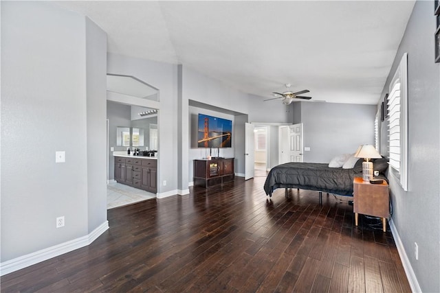 bedroom with vaulted ceiling, ensuite bath, baseboards, and wood finished floors