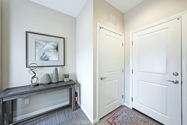 doorway featuring dark wood-style floors, baseboards, and visible vents