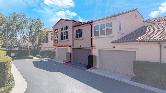 exterior space with a tiled roof, concrete driveway, an attached garage, and stucco siding