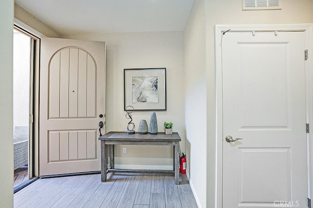 foyer with light wood-type flooring, visible vents, and baseboards