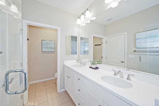 bathroom featuring toilet, a stall shower, a sink, and tile patterned floors