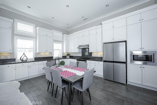 kitchen with dark countertops, appliances with stainless steel finishes, and white cabinets