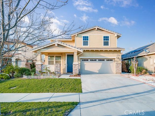 view of front of property with an attached garage, driveway, a front yard, and stucco siding