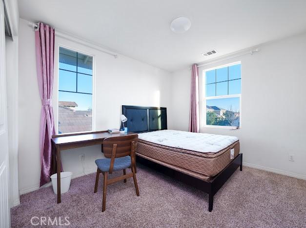 bedroom with light colored carpet, multiple windows, visible vents, and baseboards