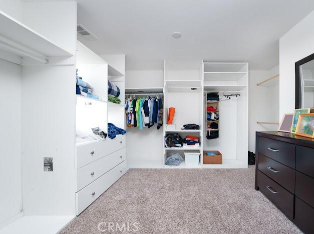 walk in closet featuring light carpet and visible vents