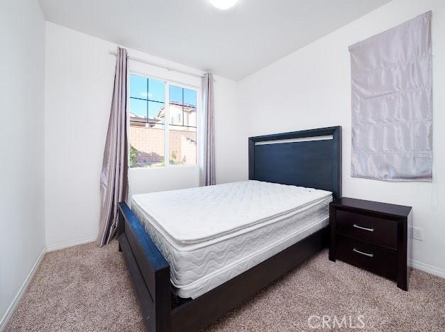 bedroom featuring light colored carpet and baseboards