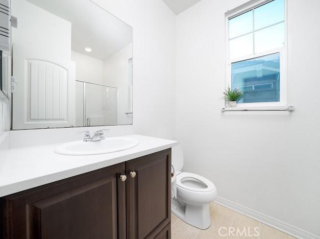 full bath featuring tile patterned flooring, toilet, vanity, baseboards, and a shower stall