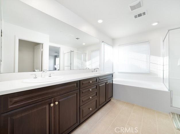 bathroom featuring a garden tub, a stall shower, a sink, and visible vents