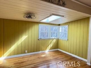 interior space featuring wooden walls, baseboards, and wood finished floors