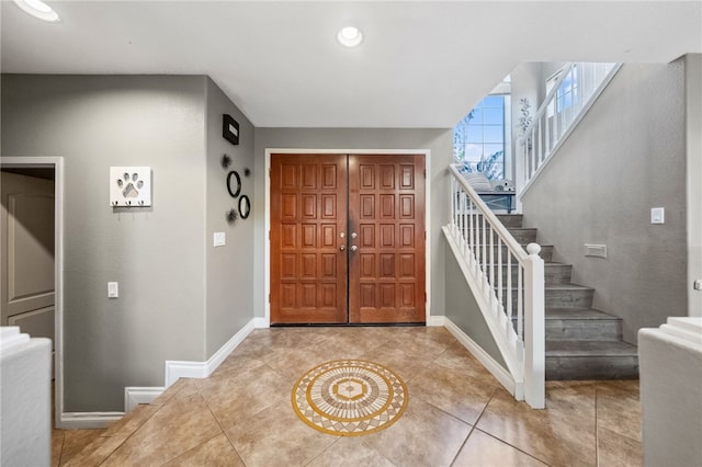 entrance foyer with light tile patterned flooring, stairway, and baseboards