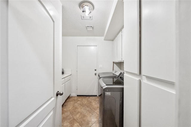 laundry area with light tile patterned floors, cabinet space, visible vents, a textured ceiling, and washer and dryer