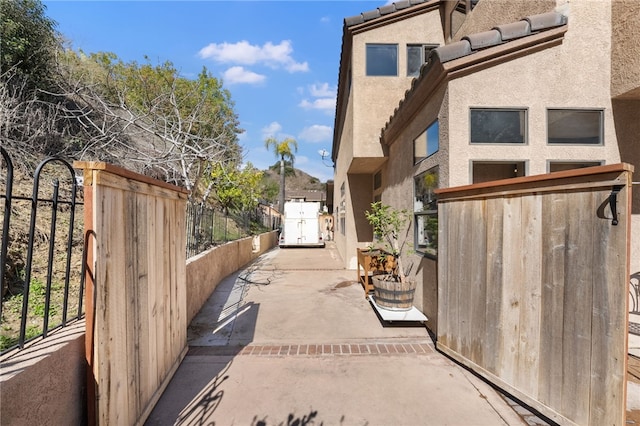 exterior space with a tiled roof, fence, a gate, and stucco siding