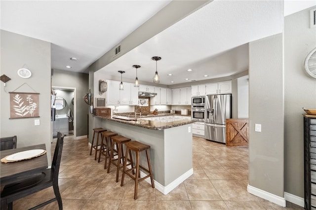 kitchen with pendant lighting, appliances with stainless steel finishes, white cabinetry, dark stone counters, and a peninsula