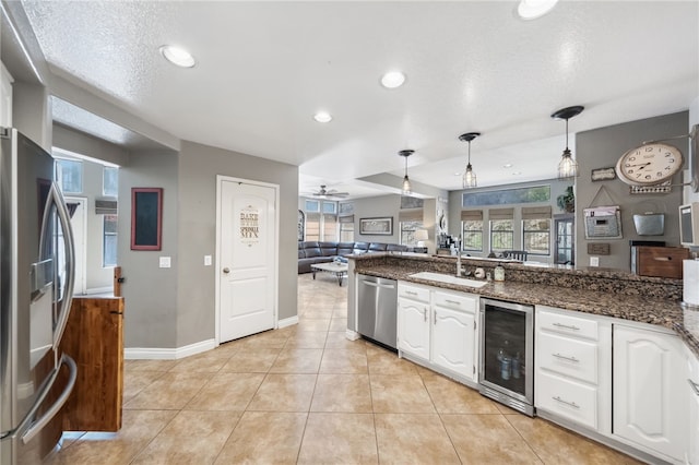 kitchen with stainless steel appliances, wine cooler, white cabinetry, and decorative light fixtures