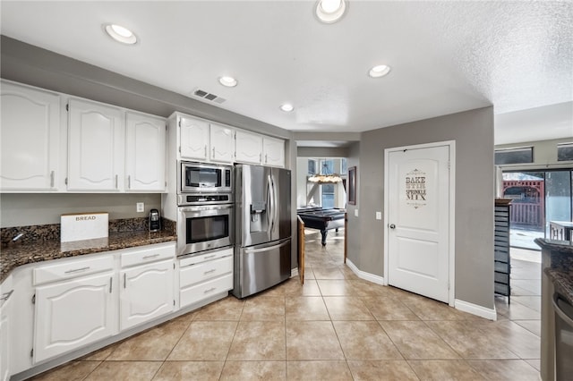 kitchen featuring light tile patterned floors, stainless steel appliances, visible vents, white cabinetry, and dark stone counters