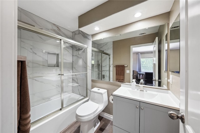 full bath with bath / shower combo with glass door, toilet, wood finished floors, vanity, and recessed lighting