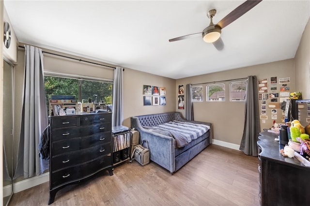 bedroom with multiple windows, baseboards, and wood finished floors