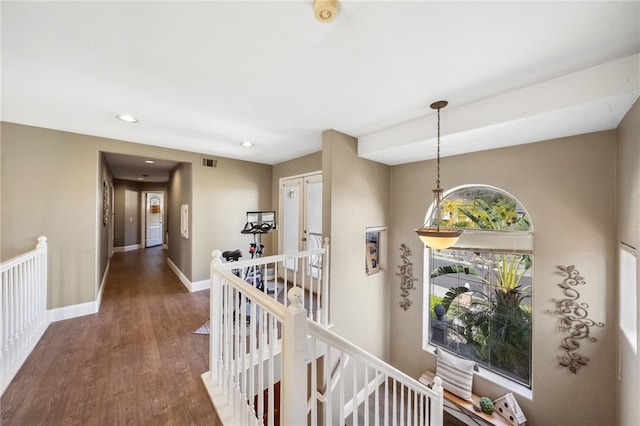 hallway with dark wood-style flooring, recessed lighting, visible vents, an upstairs landing, and baseboards