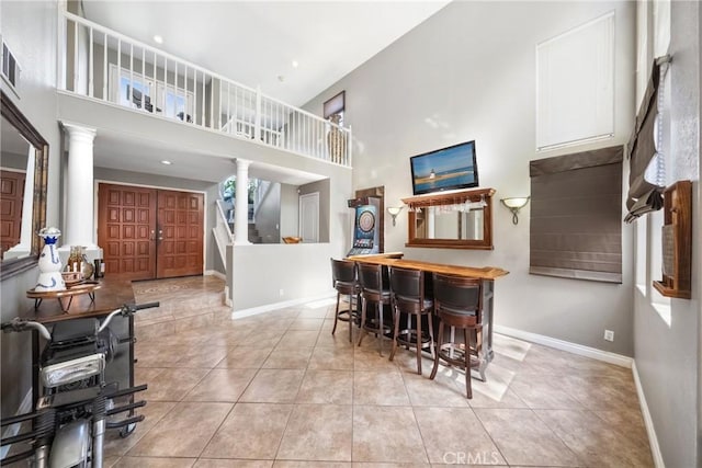 dining area featuring light tile patterned floors, decorative columns, and baseboards