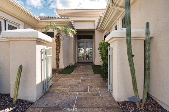 property entrance featuring stucco siding, a tile roof, a gate, and french doors