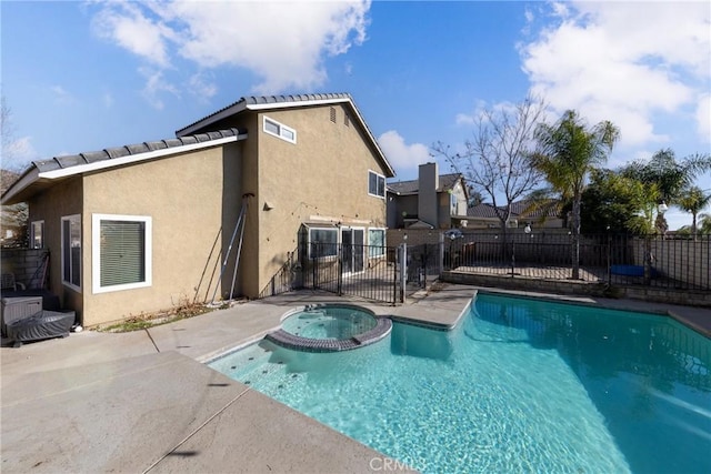 view of pool with a pool with connected hot tub, fence, and a patio