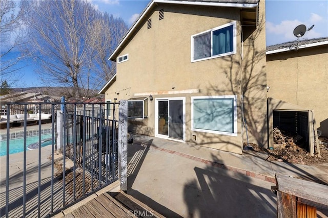 back of property featuring a patio, a fenced in pool, and stucco siding