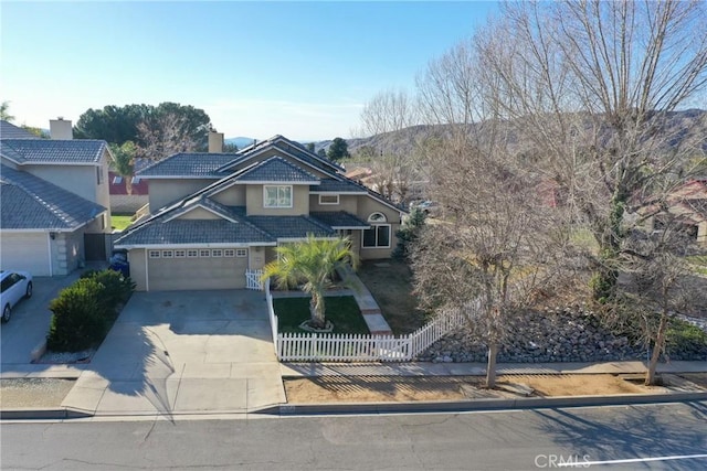 view of front of home with concrete driveway, a tile roof, an attached garage, fence, and stucco siding