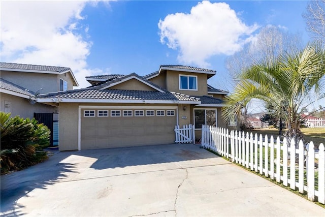 view of front of house with concrete driveway, a fenced front yard, an attached garage, and stucco siding