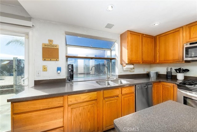 kitchen featuring stainless steel appliances, dark countertops, a wealth of natural light, and a sink