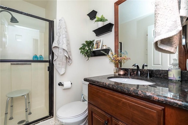 bathroom featuring a shower stall, vanity, and toilet