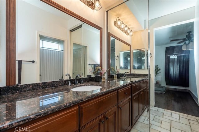 full bath with a ceiling fan, stone finish flooring, a sink, and double vanity