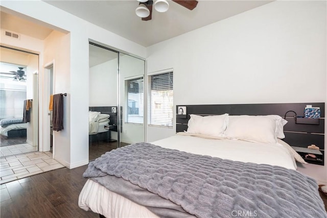 bedroom with dark wood-style flooring, a closet, visible vents, ceiling fan, and baseboards