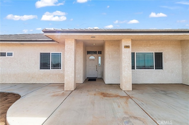 property entrance featuring a patio area and stucco siding