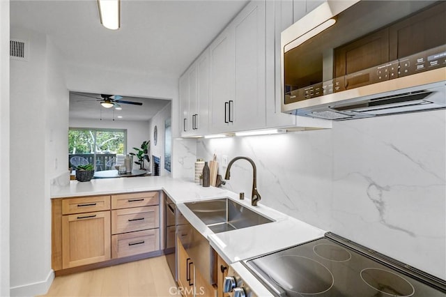 kitchen featuring visible vents, a sink, light wood-style floors, stainless steel microwave, and range