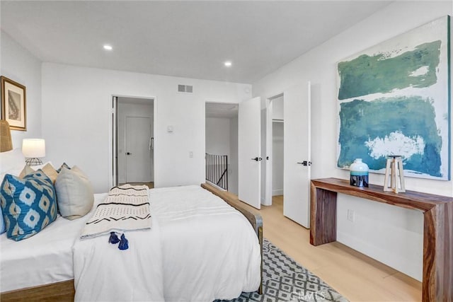 bedroom with a spacious closet, visible vents, recessed lighting, wood finished floors, and a closet