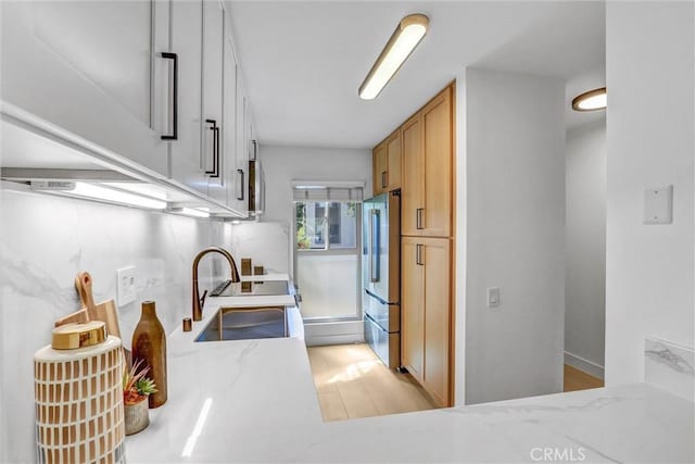 kitchen featuring light stone counters, white electric stove, high end fridge, light wood-type flooring, and backsplash