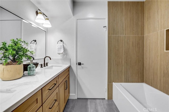 full bath featuring double vanity, a tub to relax in, and a sink